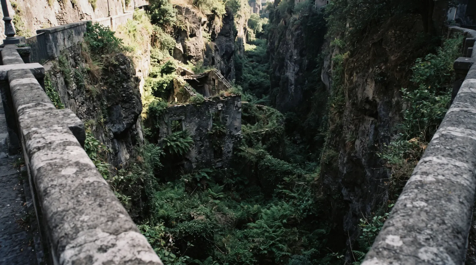 The deep green gorge of the Vallone dei Mulini in Sorrento with the ruined mill building below the railing